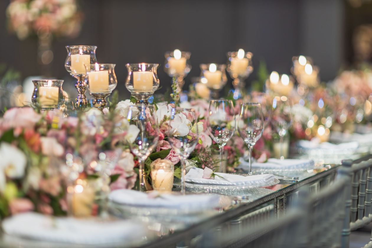 Table de réception dressée avec assiettes, verres, bougies et fleurs.