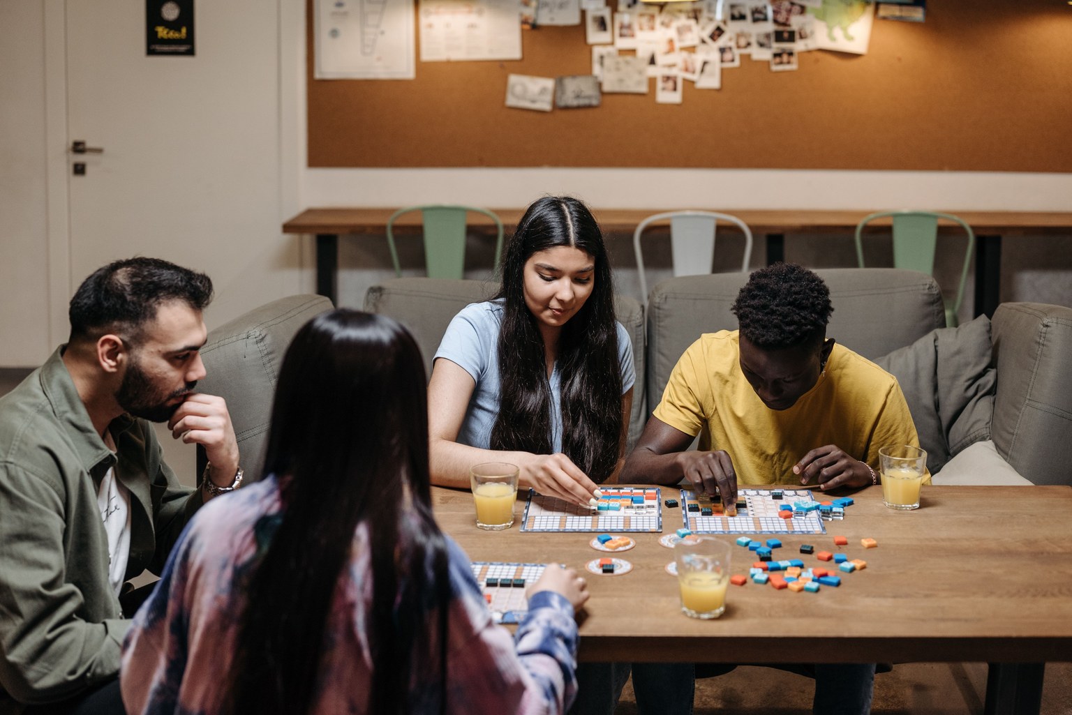 Quatre adultes jouant à un jeu de société autour d’une table en bois.