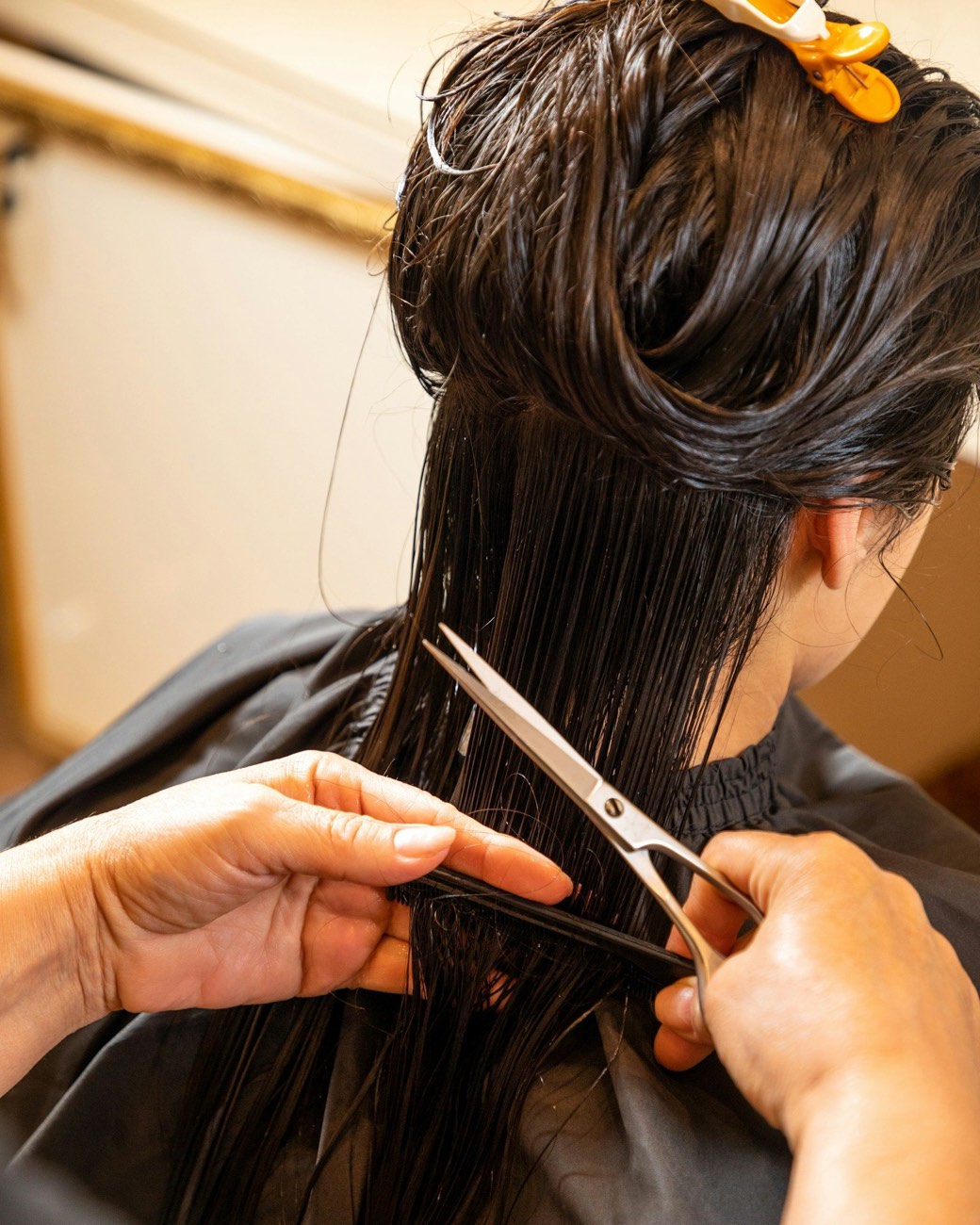Coiffeuse coupant aux ciseaux les cheveux mouillés d'une cliente au salon
