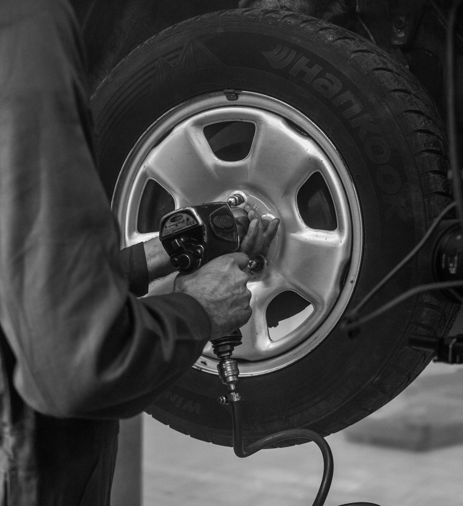 Mécanicien utilisant une clé à chocs pneumatique sur les fixations d’une roue.
