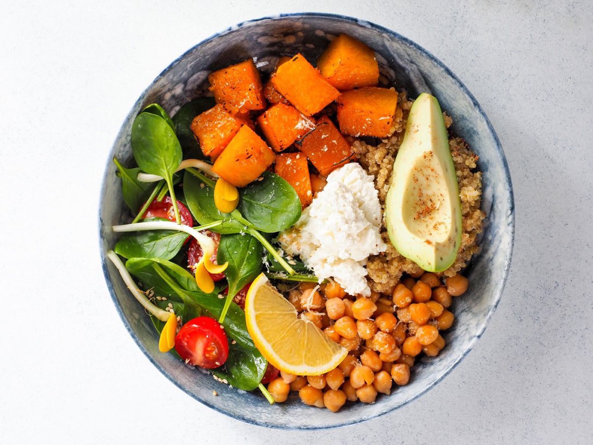 Bowl végétal vu de dessus : patate douce rôtie, pois chiches, avocat, quinoa et jeunes pousses