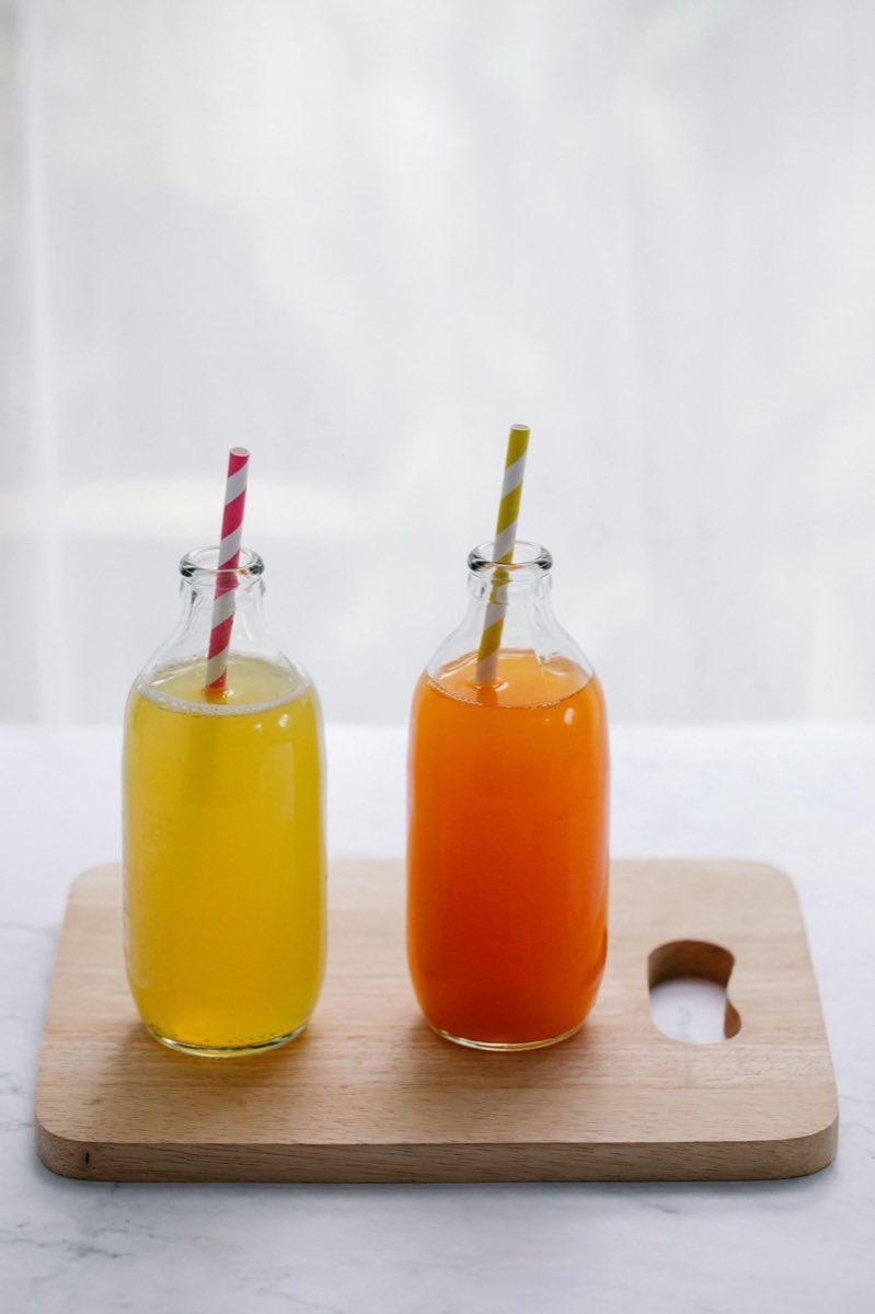 Jus pressés à la minute, servis en bouteilles de verre sur une planche