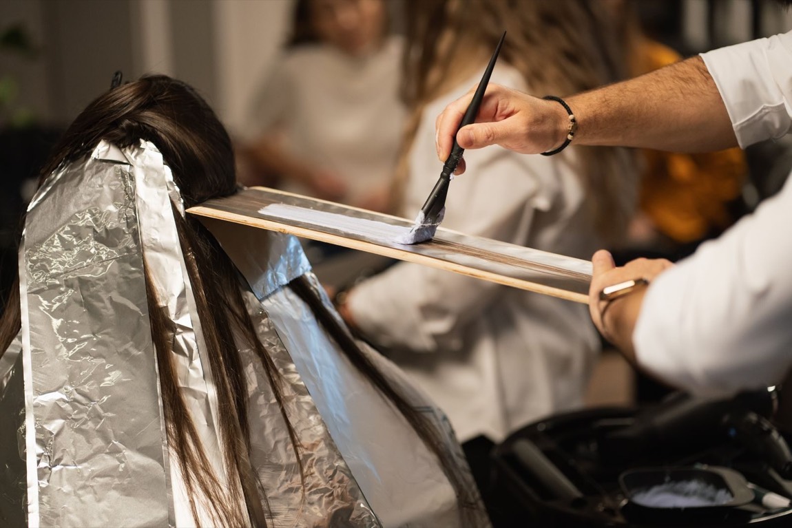 Coloriste du salon Lumen appliquant un balayage au pinceau sur une mèche posée sur planche