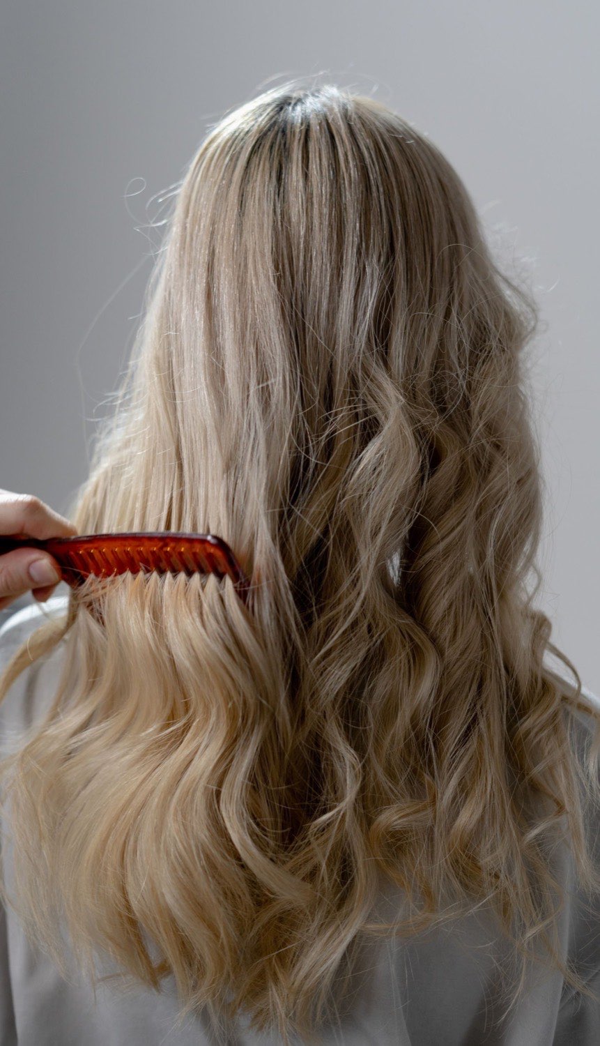 Résultat de balayage blond sur cheveux longs ondulés, vue de dos, au salon Lumen