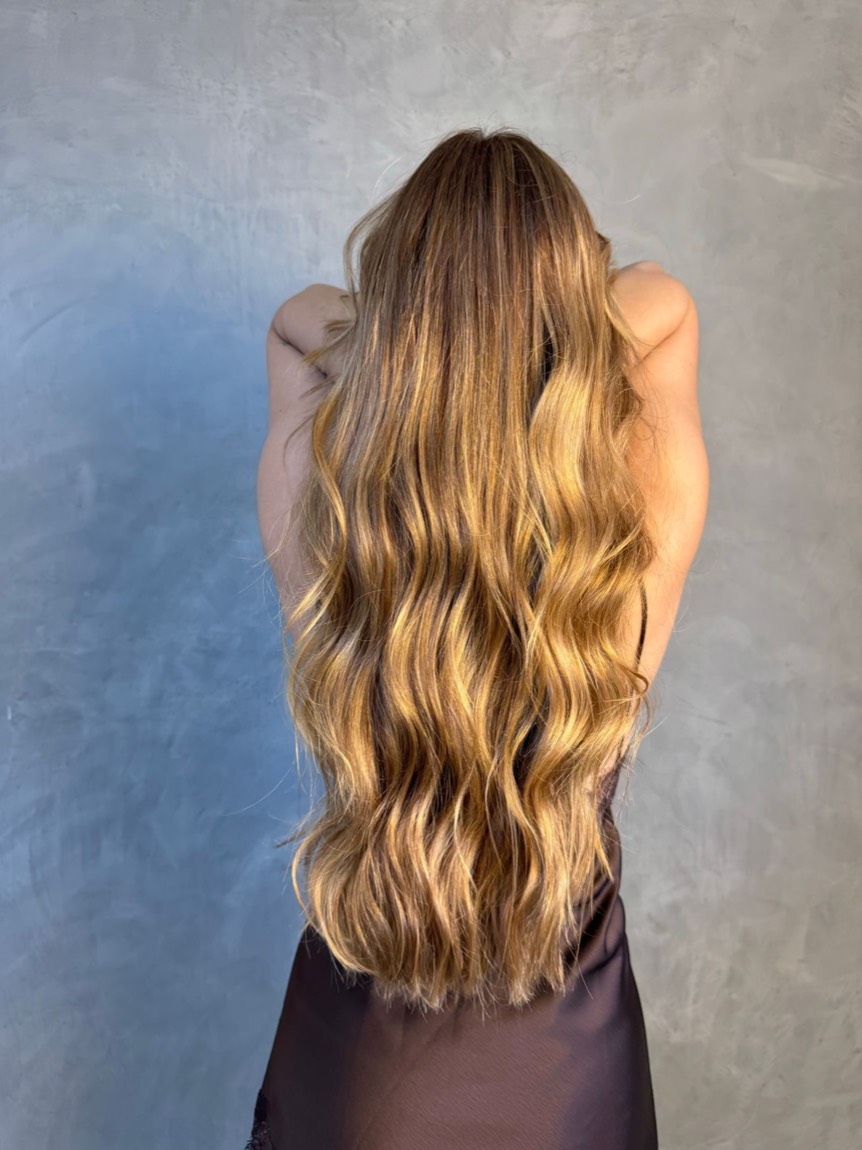Résultat de balayage caramel sur cheveux longs ondulés, vue de dos