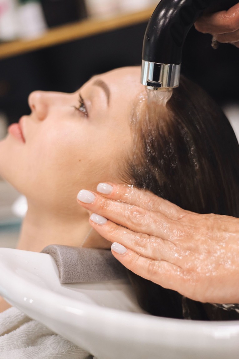 Rinçage au bac à shampoing pendant le rituel de soin du salon Lumen