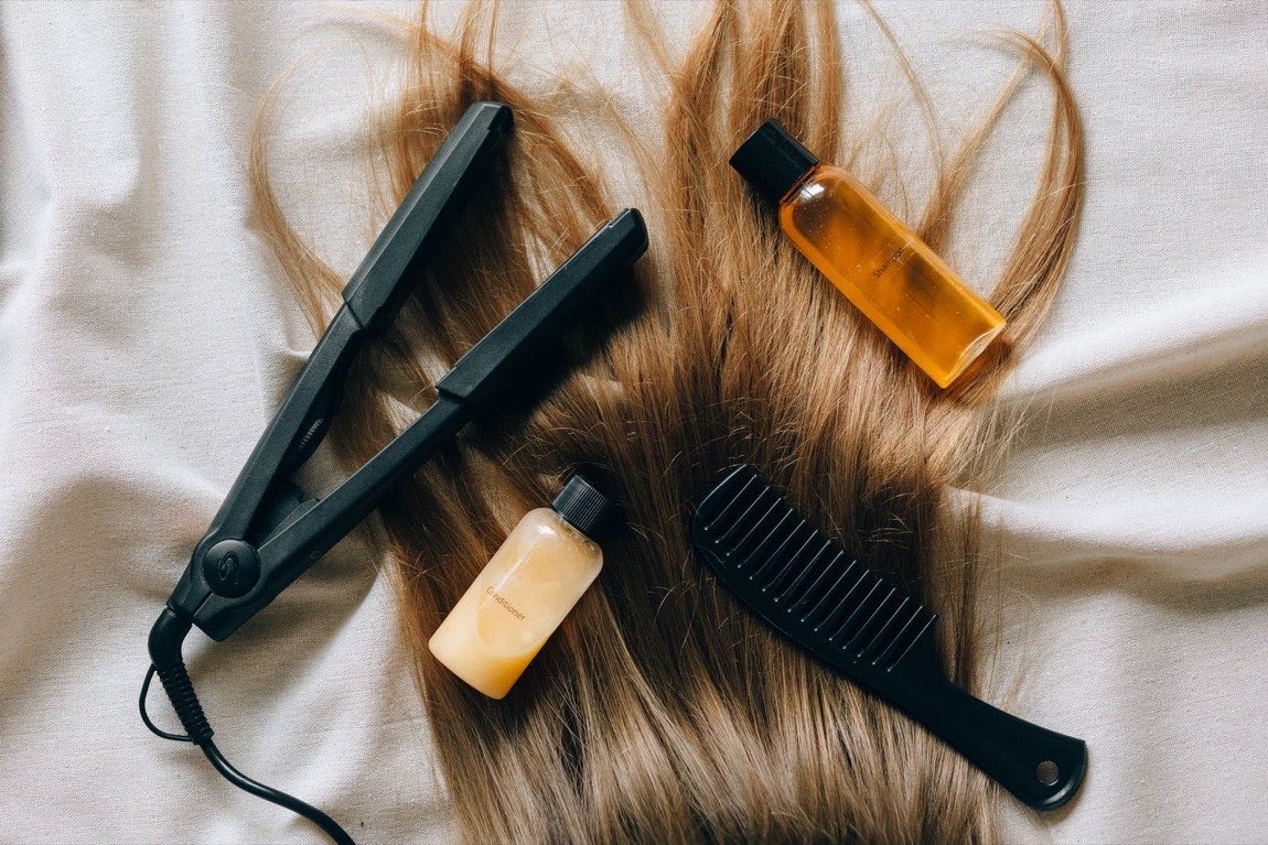 Produits et outils de coiffure posés sur un lin écru avec une mèche blonde