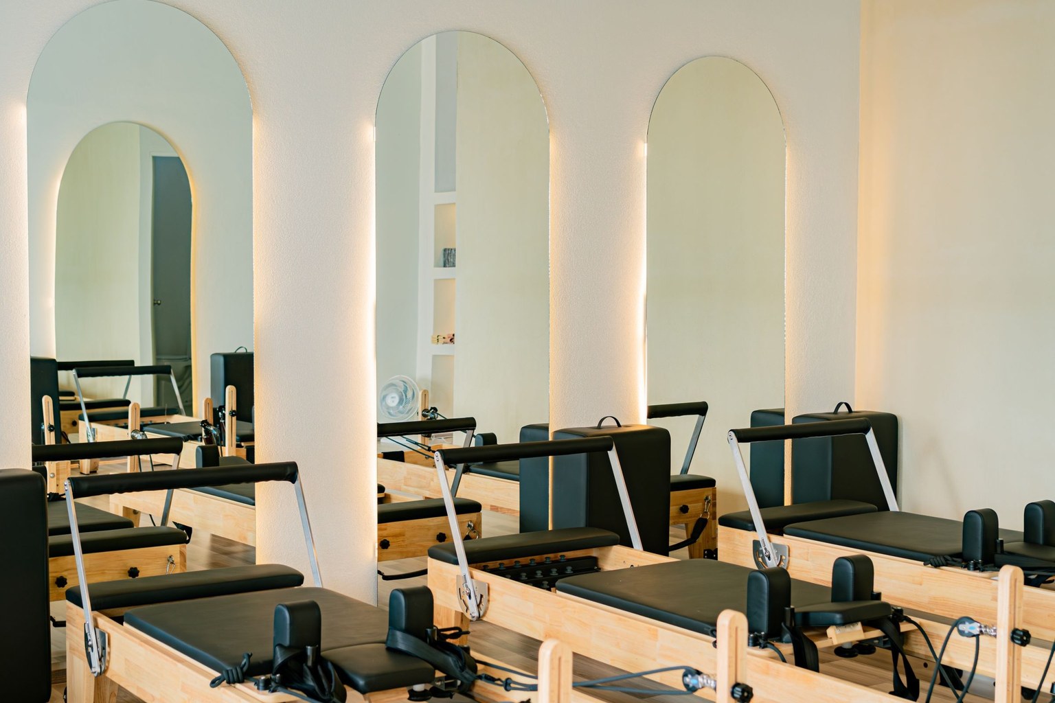 Salle lumineuse équipée de plusieurs appareils Reformer devant des miroirs.