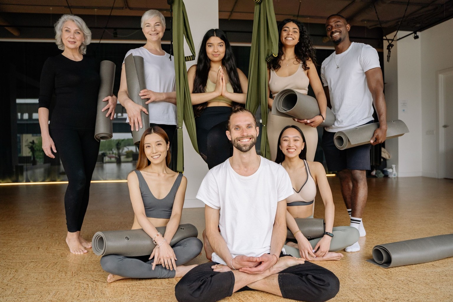Groupe de personnes debout et assises dans une salle, avec des tapis de yoga.